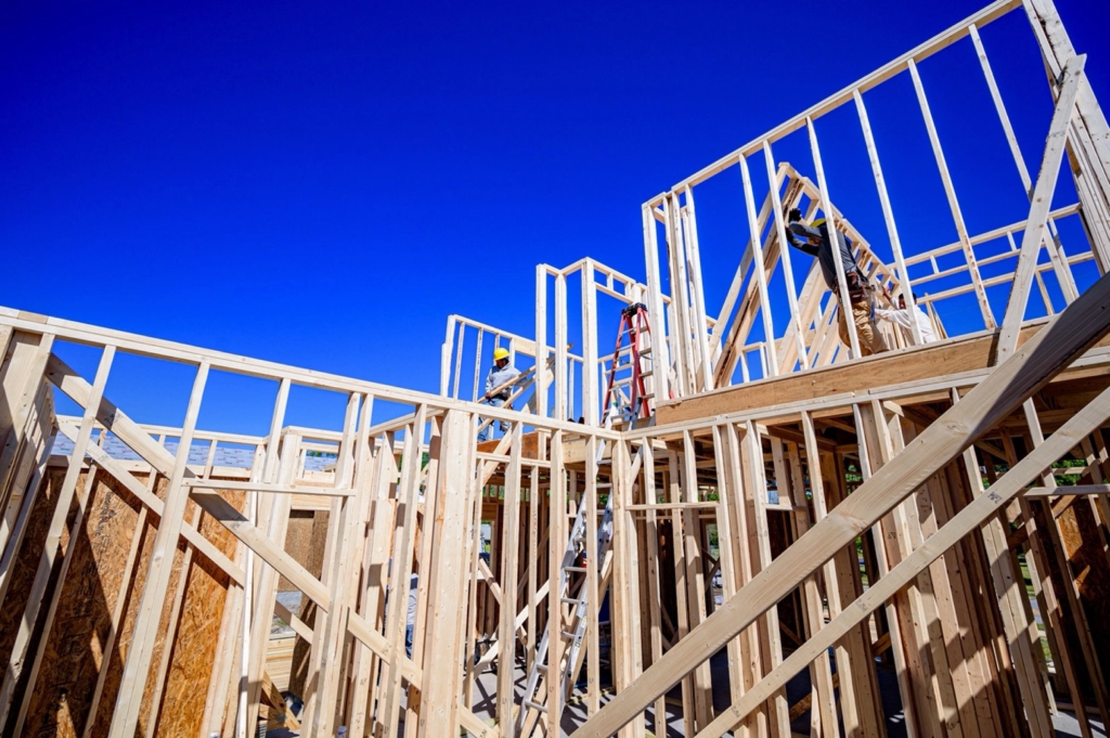 Wood framing for a two-story house against a blue sky