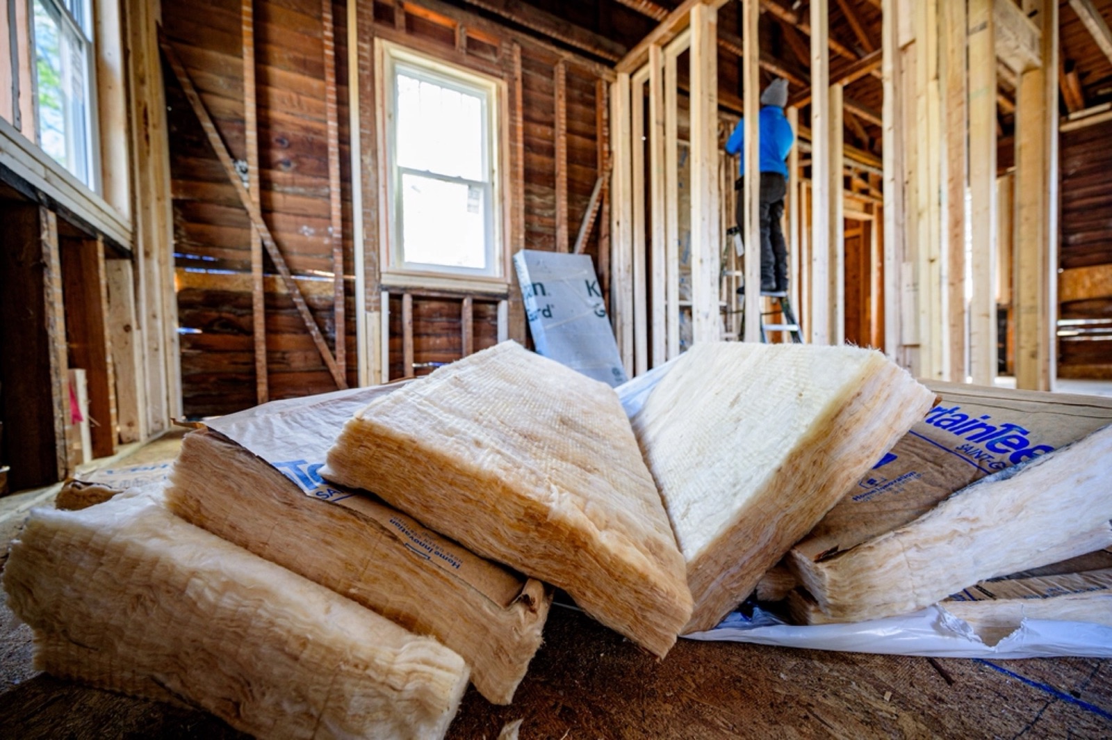 Batt insulation stacked in a room with new stud walls